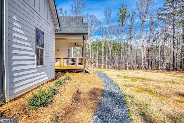 view of yard featuring a ceiling fan and a wooded view