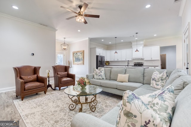 living room with light wood-style floors, visible vents, ornamental molding, and baseboards