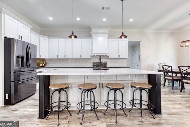 kitchen with custom exhaust hood, visible vents, appliances with stainless steel finishes, light wood-style floors, and white cabinets