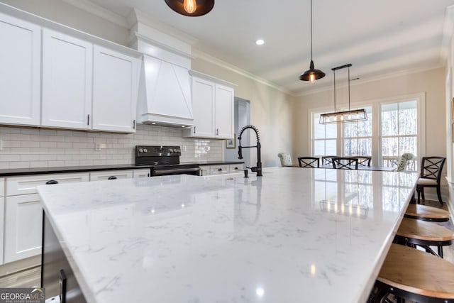 kitchen with crown molding, a breakfast bar area, decorative backsplash, and black electric range oven