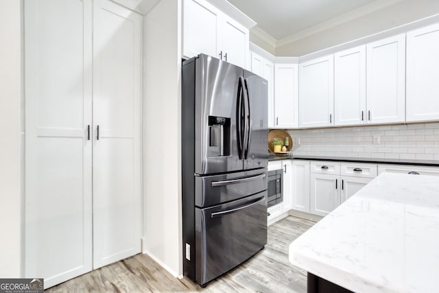 kitchen featuring appliances with stainless steel finishes, light wood-type flooring, backsplash, and white cabinetry