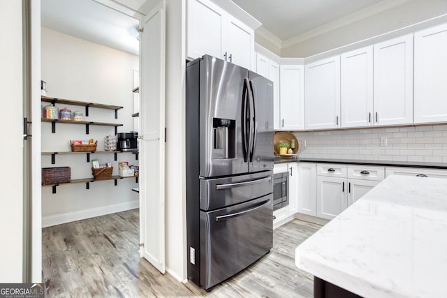 kitchen with decorative backsplash, appliances with stainless steel finishes, light stone countertops, light wood-type flooring, and white cabinetry