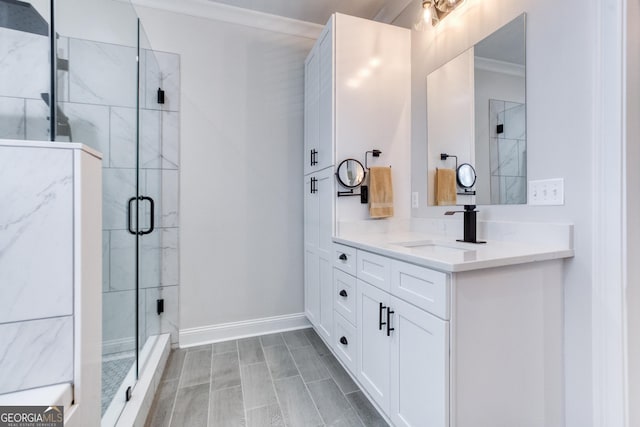 bathroom featuring ornamental molding, a shower stall, vanity, and baseboards