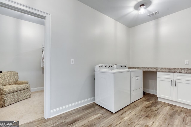 washroom featuring visible vents, baseboards, light wood-style floors, washer and dryer, and cabinet space