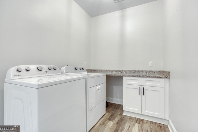 laundry room featuring baseboards, light wood-type flooring, cabinet space, and washer and dryer