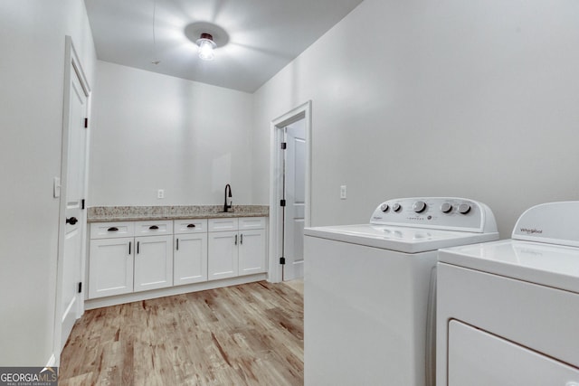 laundry area featuring independent washer and dryer, a sink, and light wood-style floors