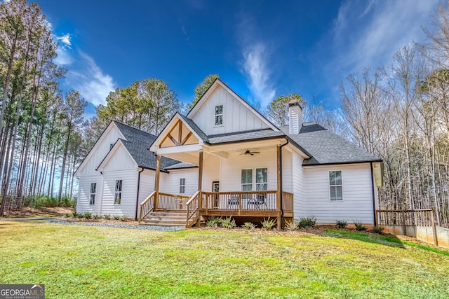 rear view of property with roof with shingles, a yard, board and batten siding, ceiling fan, and a deck