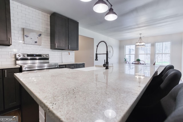 kitchen with electric range, a sink, light stone countertops, and tasteful backsplash