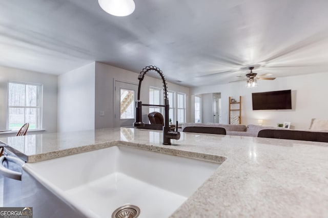 kitchen featuring open floor plan, a sink, dishwasher, and light stone countertops