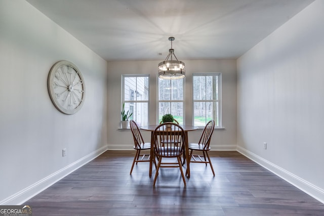 dining area with dark wood-style floors, a chandelier, and baseboards