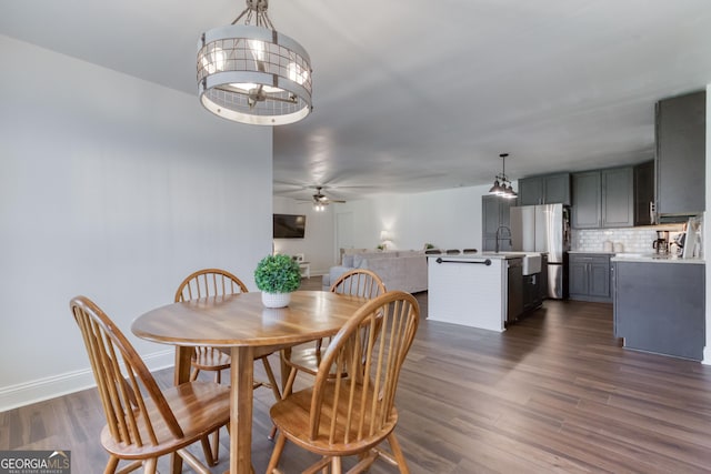 dining space featuring baseboards, dark wood finished floors, and ceiling fan with notable chandelier