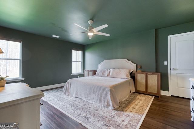 bedroom with ceiling fan, baseboards, and dark wood-style flooring