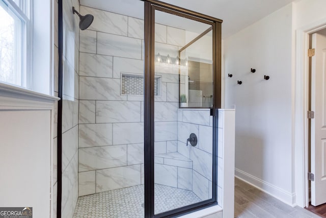 full bath with wood finished floors, a shower stall, and baseboards