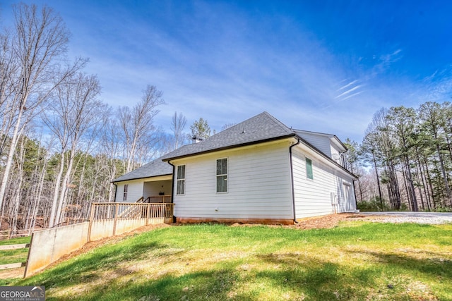 rear view of house featuring roof with shingles and a yard