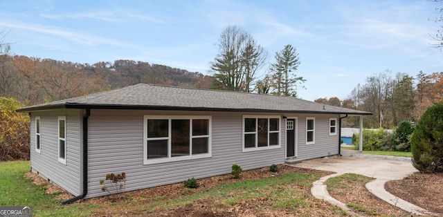 rear view of house featuring a shingled roof and a patio