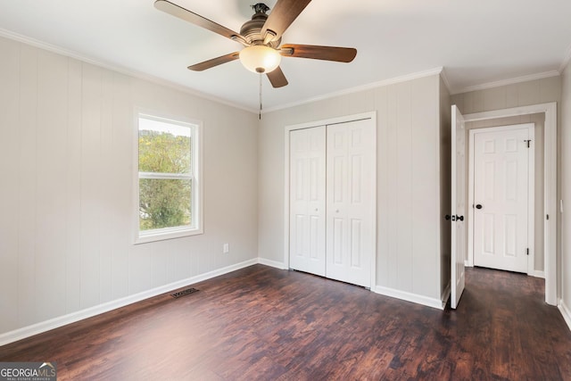 unfurnished bedroom with dark wood-type flooring, visible vents, ornamental molding, and baseboards