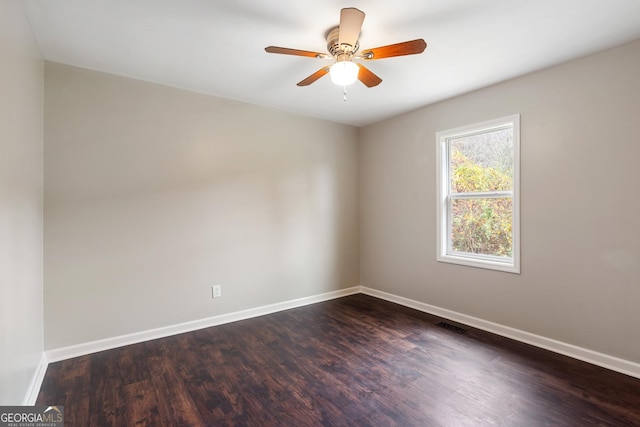 unfurnished room featuring dark wood-style floors, visible vents, baseboards, and a ceiling fan