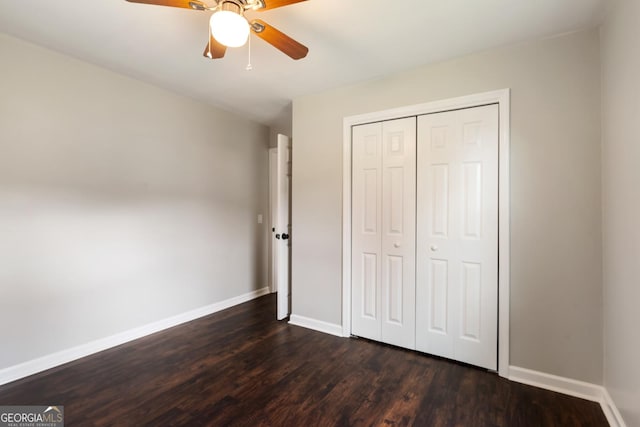 unfurnished bedroom with a closet, dark wood-style flooring, baseboards, and a ceiling fan