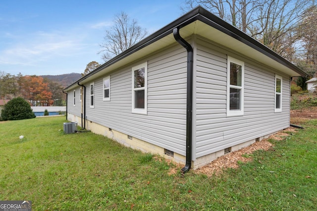 view of side of home with crawl space, a lawn, and central AC unit