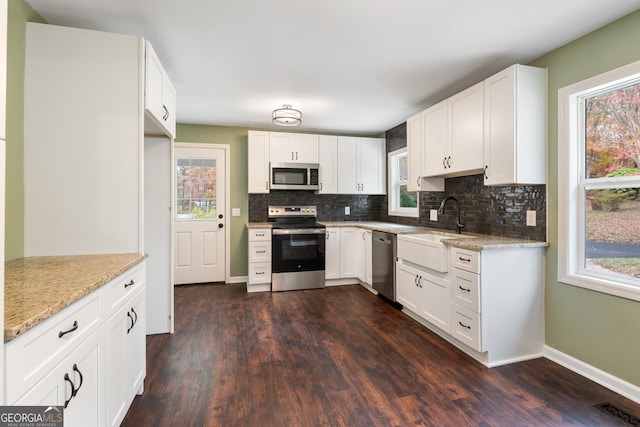 kitchen featuring dark wood-style flooring, stainless steel appliances, visible vents, decorative backsplash, and a sink