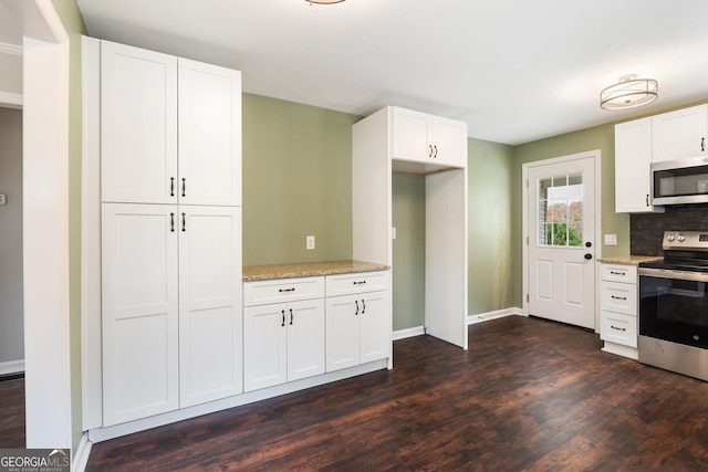 kitchen with light stone countertops, white cabinetry, stainless steel appliances, and dark wood-type flooring