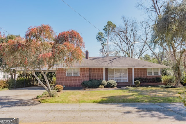 single story home featuring a carport, brick siding, a chimney, and a front yard