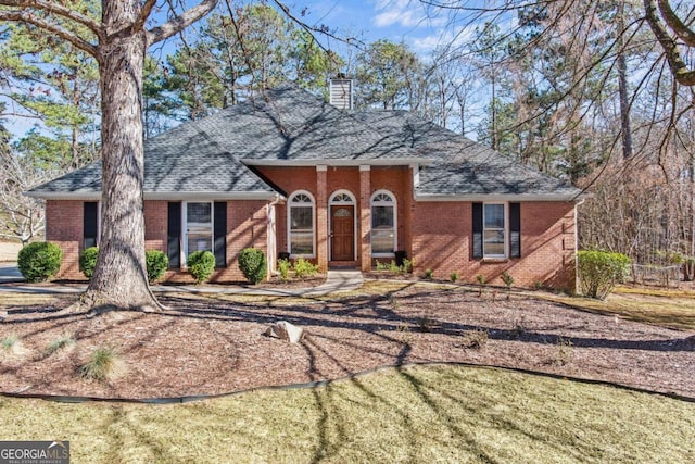 view of front of property with brick siding, a chimney, and roof with shingles