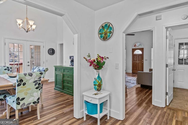 interior space featuring baseboards, french doors, wood finished floors, and a notable chandelier