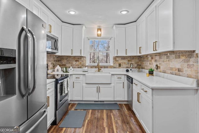 kitchen with stainless steel appliances, a sink, white cabinets, backsplash, and dark wood finished floors