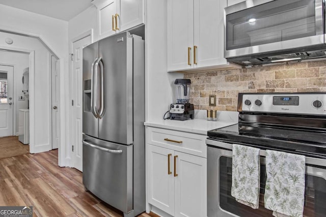 kitchen with white cabinets, light countertops, appliances with stainless steel finishes, light wood-type flooring, and decorative backsplash