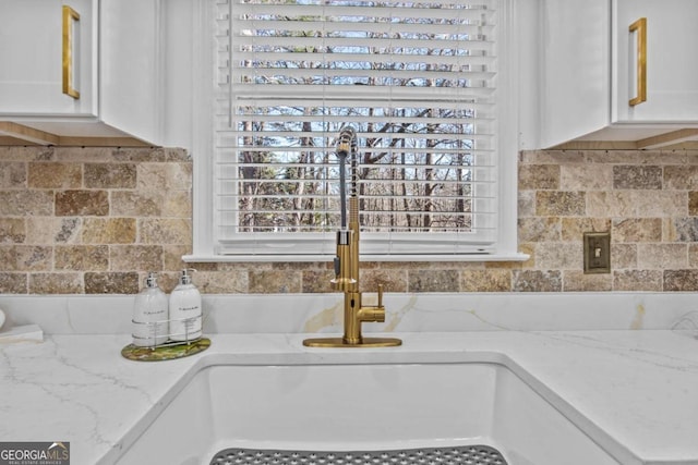 details with light stone countertops, white cabinets, and a sink