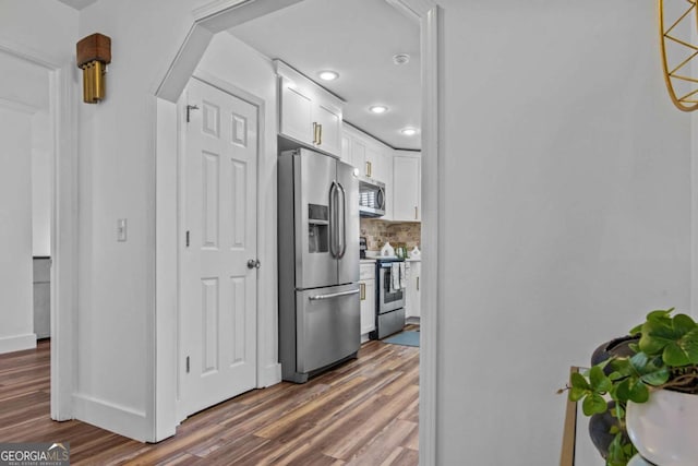 kitchen featuring baseboards, dark wood-type flooring, stainless steel appliances, white cabinetry, and backsplash