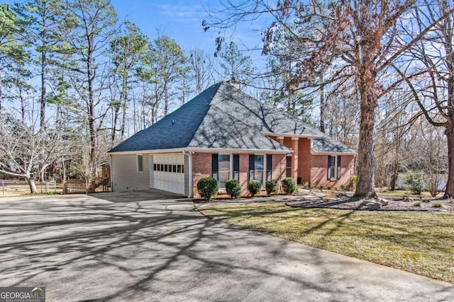 view of front facade featuring brick siding, a shingled roof, a front yard, a garage, and driveway