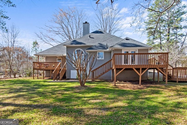 rear view of house featuring a deck, a shingled roof, stairs, a lawn, and a chimney