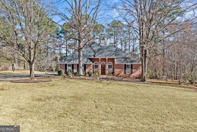 view of front of home with a front lawn, a chimney, and brick siding