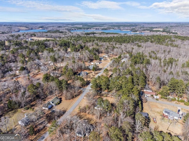 birds eye view of property featuring a water view and a wooded view