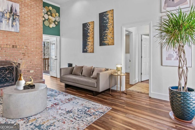 living area with a fireplace, baseboards, wood finished floors, and ornamental molding