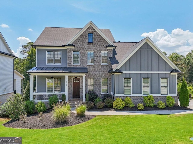 craftsman-style home with brick siding, roof with shingles, a porch, board and batten siding, and a front lawn