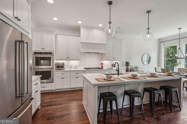 kitchen featuring appliances with stainless steel finishes, light countertops, a sink, and a kitchen breakfast bar