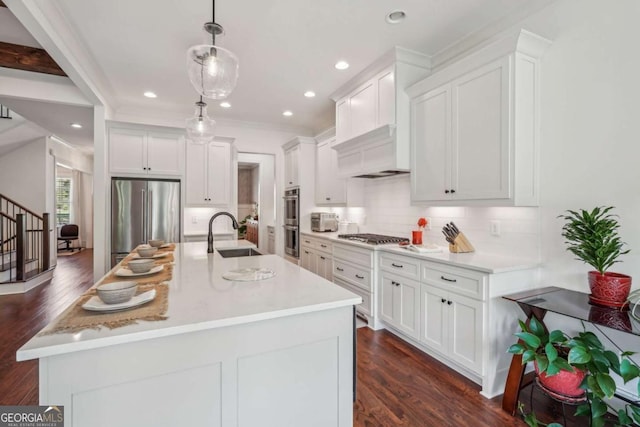 kitchen with appliances with stainless steel finishes, white cabinets, a sink, and tasteful backsplash