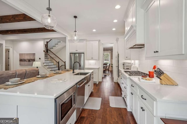 kitchen featuring stainless steel appliances, a sink, white cabinets, tasteful backsplash, and dark wood finished floors