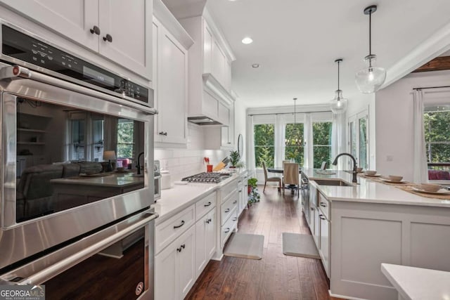 kitchen featuring stainless steel appliances, white cabinetry, dark wood finished floors, and backsplash