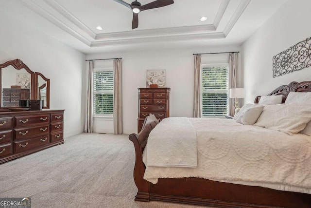 carpeted bedroom featuring a ceiling fan, a raised ceiling, crown molding, and baseboards