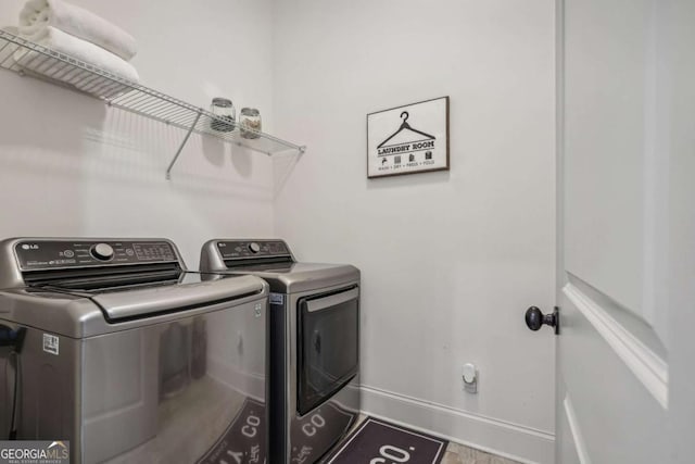 clothes washing area with laundry area, baseboards, and washing machine and clothes dryer