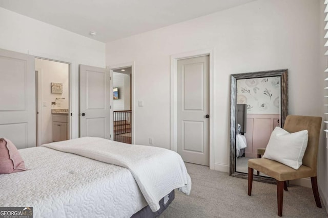 bedroom with connected bathroom and light colored carpet