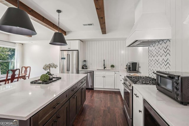 kitchen featuring appliances with stainless steel finishes, visible vents, custom range hood, and beamed ceiling