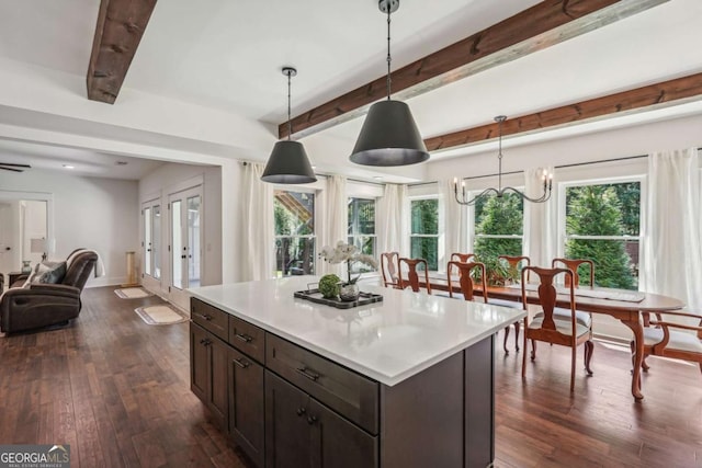 kitchen featuring dark wood-style flooring, beam ceiling, light countertops, hanging light fixtures, and open floor plan