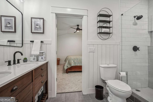 ensuite bathroom featuring ensuite bathroom, toilet, a wainscoted wall, a sink, and tiled shower