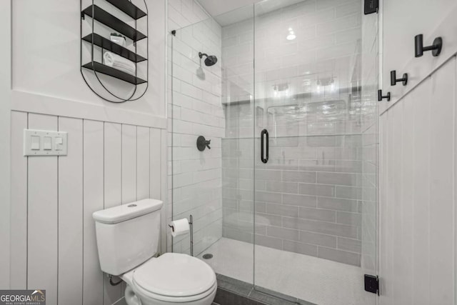 full bathroom featuring toilet, a wainscoted wall, and a shower stall