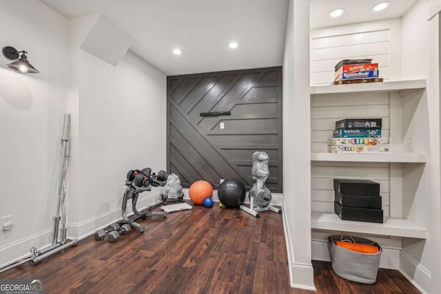 exercise room featuring built in shelves, recessed lighting, baseboards, and wood finished floors